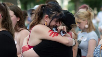 2022年6月24日，19岁的托佩坎·切尔·伊斯利(左)在堪萨斯州托皮卡州议会大厦举行的集会上拥抱她的朋友。