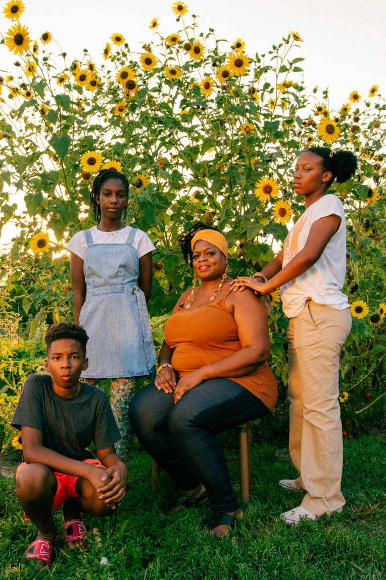 奥古斯特的花园治疗团队站在向日葵的背景下。(从左顺时针方向)Riyad Ba, 11岁，Zara Ba, 13岁，Denise Perkins在中间，Liberty Williams, 13岁，上课前。(Ji Stribling | Flatland)