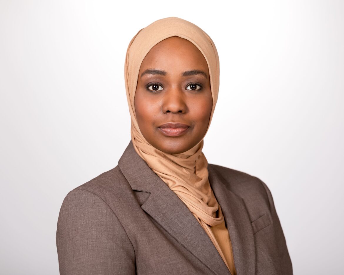 伊萨·哈萨巴拉(Ithar Hassaballah)是堪萨斯大学医学中心的健康公平评估项目经理，他头戴褐色头巾，身穿棕色西装。