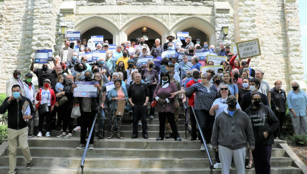 一群人站在台阶上举着牌子微笑。